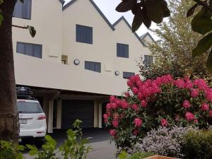 a car parked in front of a building with pink flowers at Bella Vista Motel & Apartments Christchurch in Christchurch