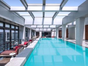 uma grande piscina com cadeiras vermelhas num edifício em Cordis Shanghai Hongqiao (Langham Hospitality Group) em Xangai