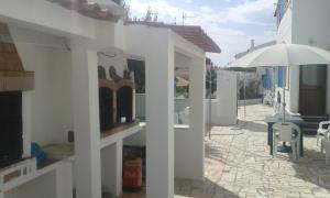 ein weißes Gebäude mit einem Sonnenschirm und einer Terrasse in der Unterkunft Apartamentos Campos 2 in Porto Covo