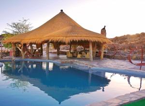 a large straw hut with a swimming pool at Rostock Ritz Desert Lodge in Cha-re
