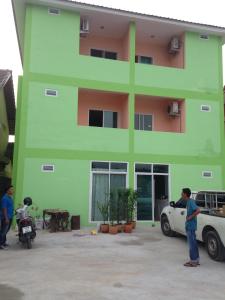 Nong Prue的住宿－健一公寓，站在绿色建筑前的人