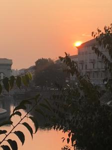 einen Sonnenuntergang über einem Wasserkörper mit einem Gebäude in der Unterkunft Living in Mailand