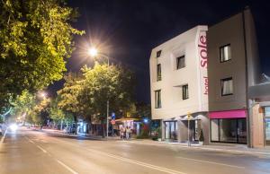 une rue de la ville la nuit avec un bâtiment dans l'établissement Hotel Sole, à Niš