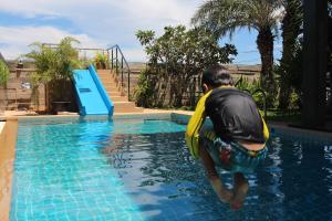 un hombre en una piscina con chaleco salvavidas junto a un tobogán de agua en Goodhope Villa en Sam Roi Yot