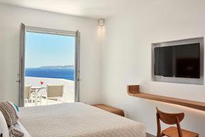 a bedroom with a bed and a flat screen tv at Manoula's Beach Mykonos Resort in Agios Ioannis Mykonos