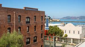 - un bâtiment en briques rouges avec un panneau sur un balcon dans l'établissement Argonaut Hotel, a Noble House Hotel, à San Francisco