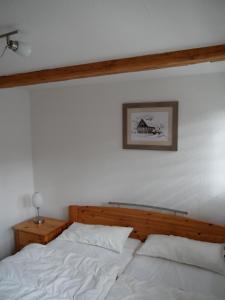 łóżko z białą pościelą i zdjęciem na ścianie w obiekcie Ferienhaus Am Skihang w mieście Altenberg