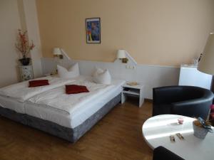 a bedroom with a large white bed and a chair at Hotel Elisenhof in Chemnitz