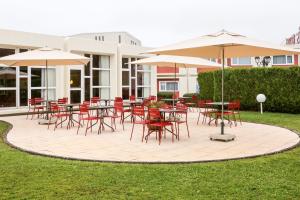 un patio avec des tables, des chaises et des parasols dans l'établissement ibis Charleville Mézières, à Villers-Semeuse