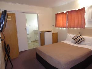 a bedroom with a bed and a dresser at Moondarra Motel in Innisfail
