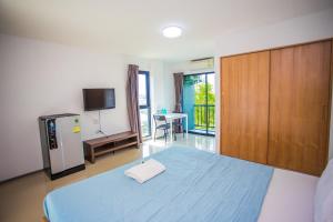 1 dormitorio con 1 cama azul y TV en Promsook Apartment en Bangsaen