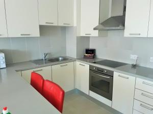 a kitchen with white cabinets and a sink and a red chair at 16 SANDY BEACH in Larnaca +21 photos
