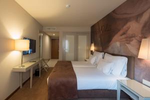 a hotel room with a bed and a television at Vila Gale Porto Ribeira in Porto