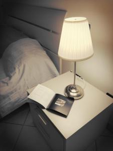 a lamp on a table next to a bed with a book at Casa Solemare in Diano Marina