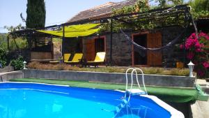 a house with a swimming pool in front of a house at Ocean View Cottage in Arco da Calheta