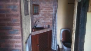 a bathroom with a sink and a brick wall at Ocean View Cottage in Arco da Calheta +22 photos