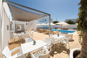 une terrasse avec des tables et des chaises blanches et une piscine dans l'établissement Villa Irena Bianca, à Náoussa