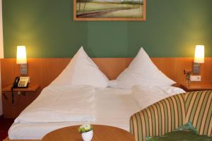 Habitación de hotel con cama con almohadas blancas y teléfono en Hotel Häußler en Langenbruck