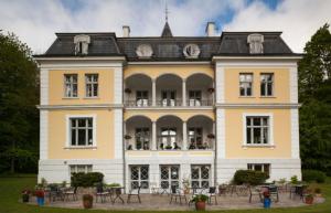 a large yellow building with tables in front of it at Liselund Ny Slot Hotel in Borre