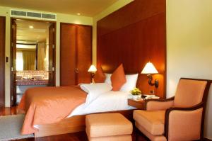 - une chambre avec un grand lit et une chaise dans l'établissement Mission Hills Phuket Golf Resort-SHA Extra Plus, à Por Bay