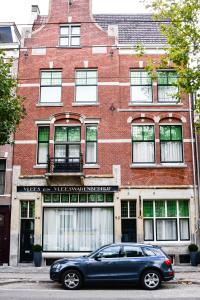 een blauwe auto geparkeerd voor een bakstenen gebouw bij De Jonker Urban Studios & Suites in Amsterdam