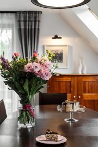 a vase of flowers on a table with a cake at Apartament nad Cukiernią in Zakopane