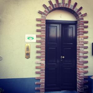 una porta nera su un muro di mattoni con arco in mattoni di B & B La Guesthouse a Poirino