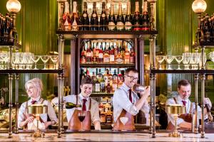 a group of men standing behind a bar with wine glasses at The Langham London in London