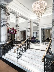 a lobby with a staircase and a chandelier at The Langham London in London