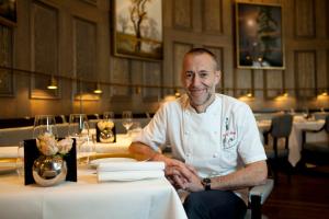 a man sitting at a table in a restaurant at The Langham London in London