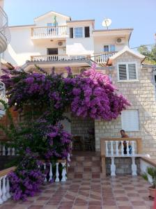 dom z fioletowymi kwiatami wiszącymi nad patio w obiekcie Apartmani Kalinic w mieście Bijela