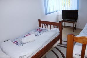 Dormitorio pequeño con cama y TV en Guest House Business, en Valpovo
