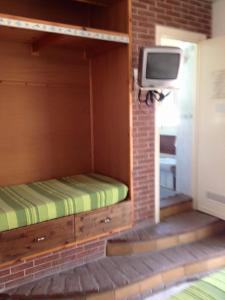 a bed in a room with a tv on a brick wall at La veranda in Ardea