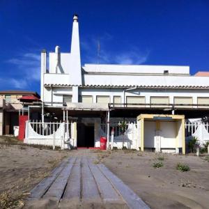 a white building with a red door and a tower at La veranda in Ardea