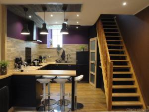 a kitchen with purple walls and a kitchen island with bar stools at Gîte Le Vintage in Saint-Émilion