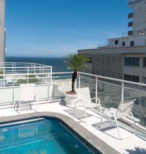 un balcón con sillas, una piscina y el océano en South Beach Vista Mar Apartamentos, en Río de Janeiro