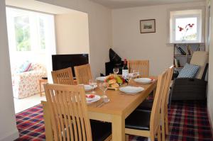 a dining room with a wooden table and chairs at Gorsnavoon Cottage in Clachaig