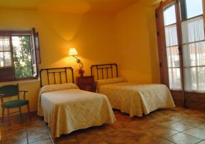 a bedroom with two beds and a chair and windows at Casa Rural Las Avutardas in Sierra de Fuentes