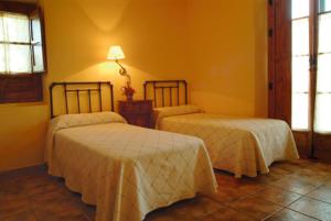 a bedroom with two beds and a lamp on the wall at Casa Rural Las Avutardas in Sierra de Fuentes