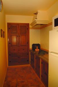 - une cuisine avec des placards en bois et un réfrigérateur blanc dans l'établissement Casa Rural Las Avutardas, à Sierra de Fuentes