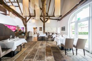 een restaurant met witte tafels en stoelen en grote ramen bij Hof Veldink in Emlichheim