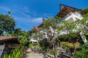 a large white building with trees in front of it at Cocohut Beach Resort Koh Phangan in Haad Rin