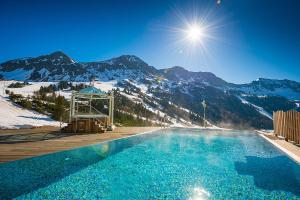 a swimming pool with snow covered mountains in the background at Sporthotel Cinderella in Obertauern
