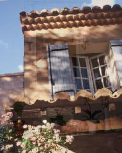 un edificio con una ventana y flores delante de él en Logis Hôtel restaurant des Pins en Bédoin