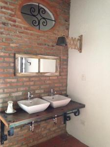 a bathroom with two sinks and a brick wall at Casa Verde Albarrada in Mompos