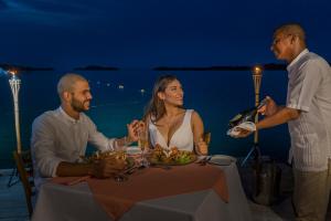 un grupo de personas sentadas alrededor de una mesa con un plato de comida en Aura Hotel Barú, en Barú