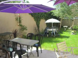 un gruppo di tavoli e sedie con ombrelloni viola di Maison Saint Louis a Paray-le-Monial