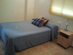 a bedroom with a blue bed with pillows and a night stand at Hostal Arneva Orihuela in Arneva