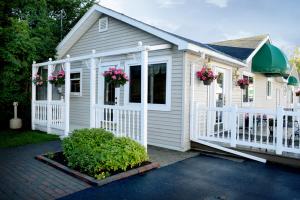 une maison blanche avec une clôture blanche et des fleurs dans l'établissement adoba® Lockview, à Sault-Sainte-Marie