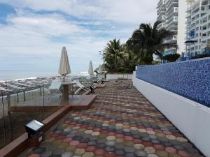 una pasarela con mesas y sombrillas junto a la playa en Departamento frente al mar Grand Diamond, en Tonsupa